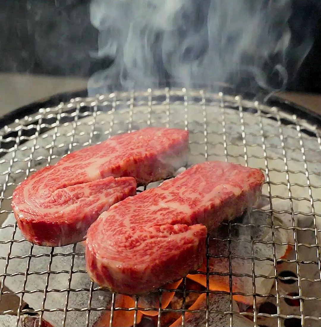 炭火の網に並ぶ厚切り牛肉