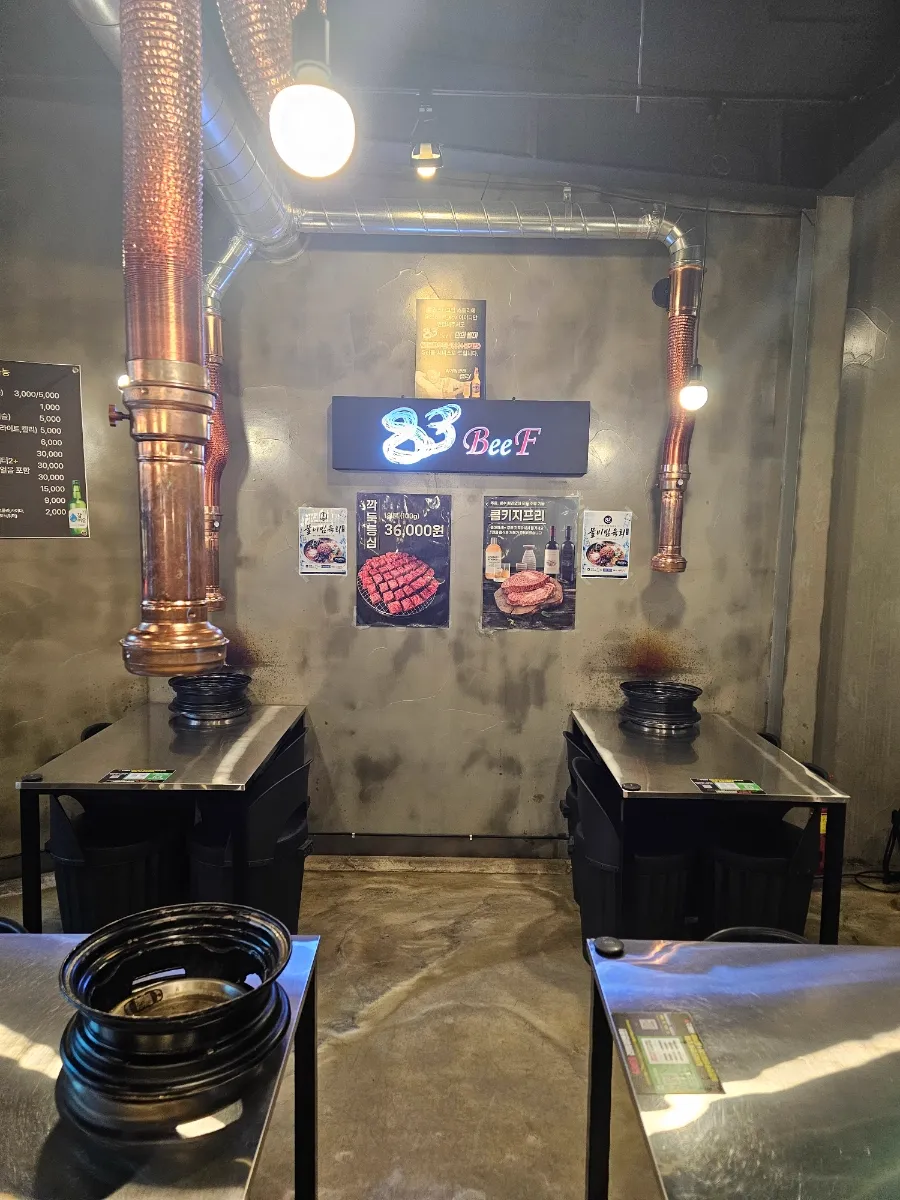 83BeeF 東莱本店 — 銅の排煙ダクトと83の看板がある客席