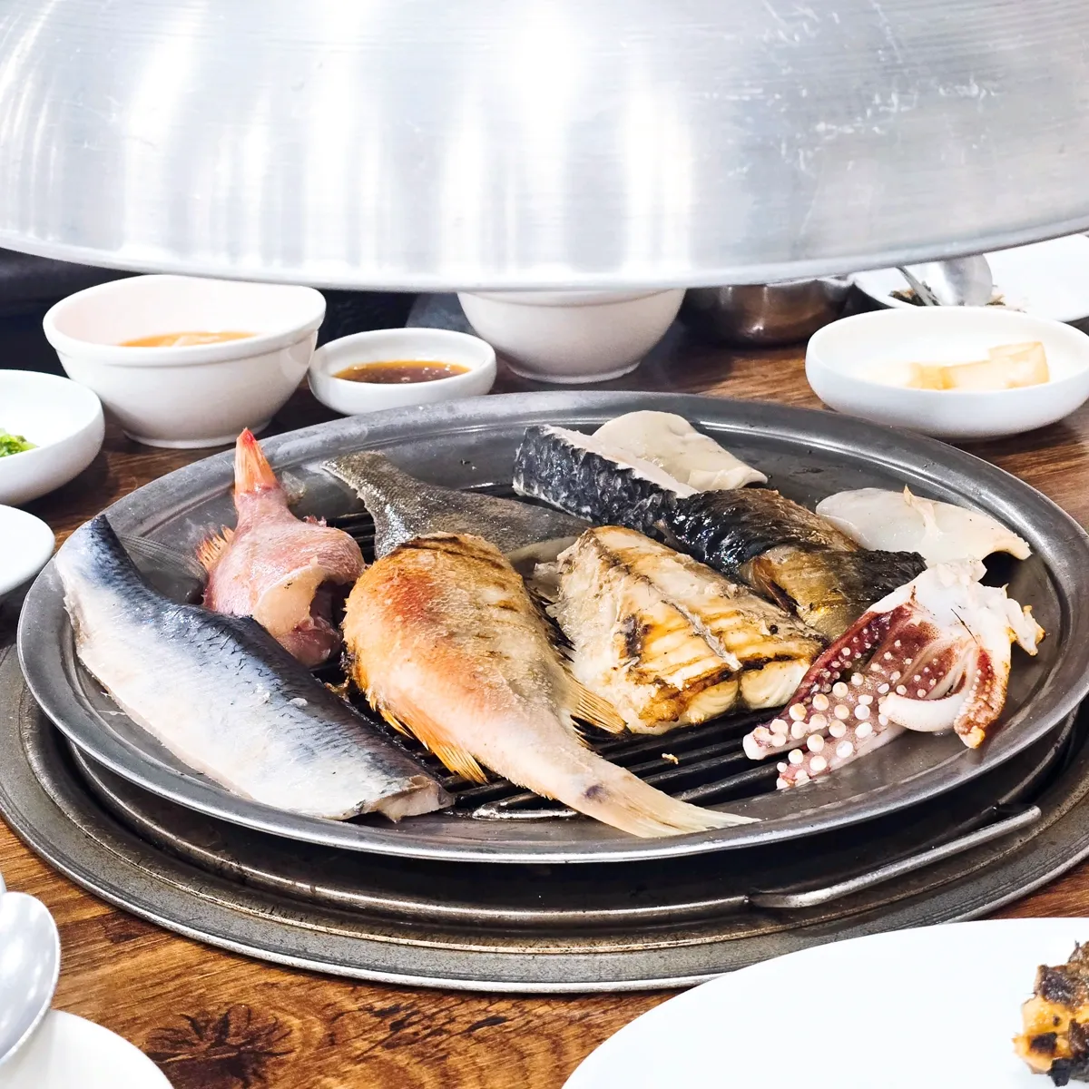 フードの下で焼ける魚とイカの盛り合わせ