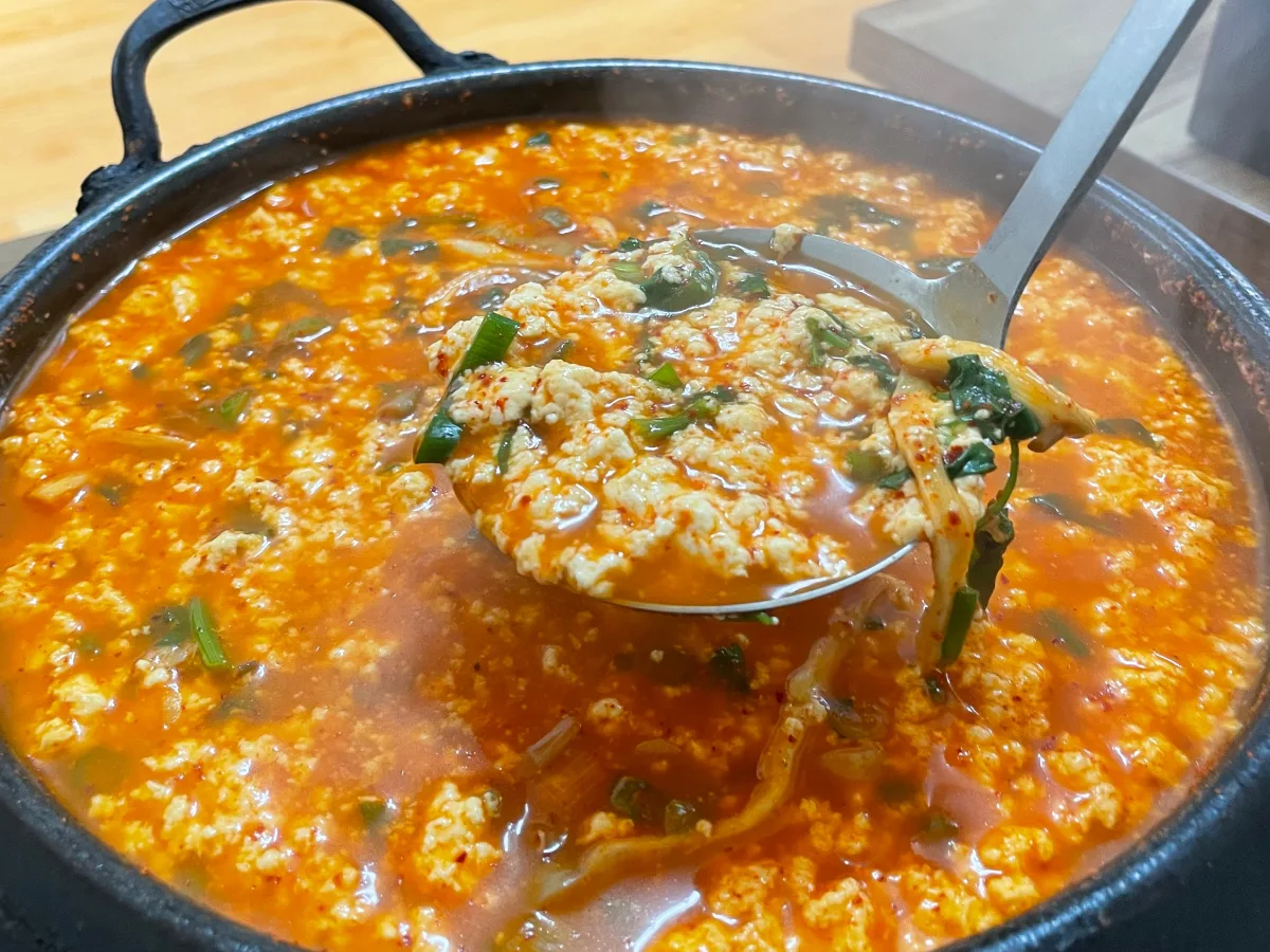 クナムメ・トゥブジプ — 赤いスープの豆腐をお玉ですくう
