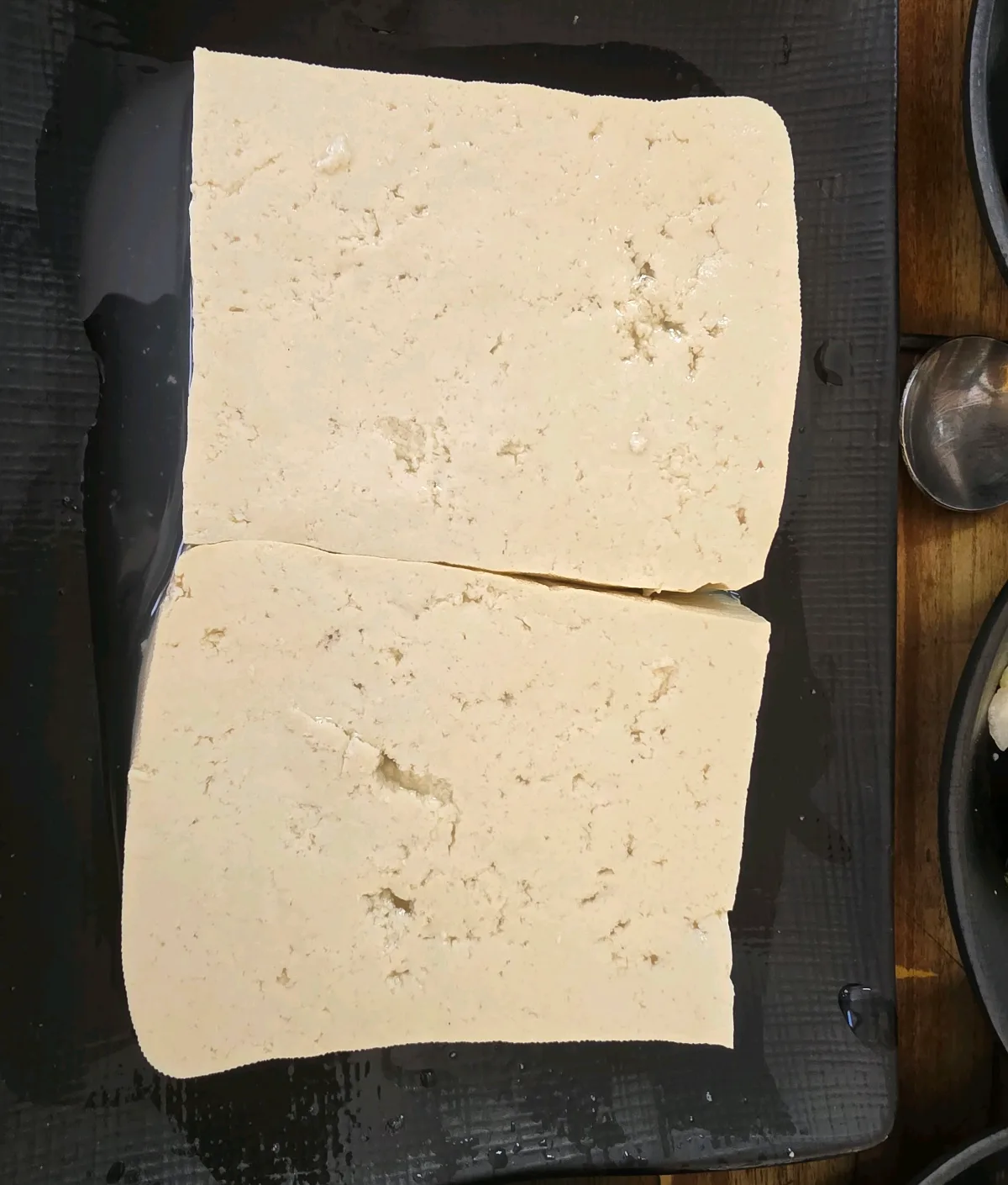 黒い角皿に盛られた二切れの豆腐