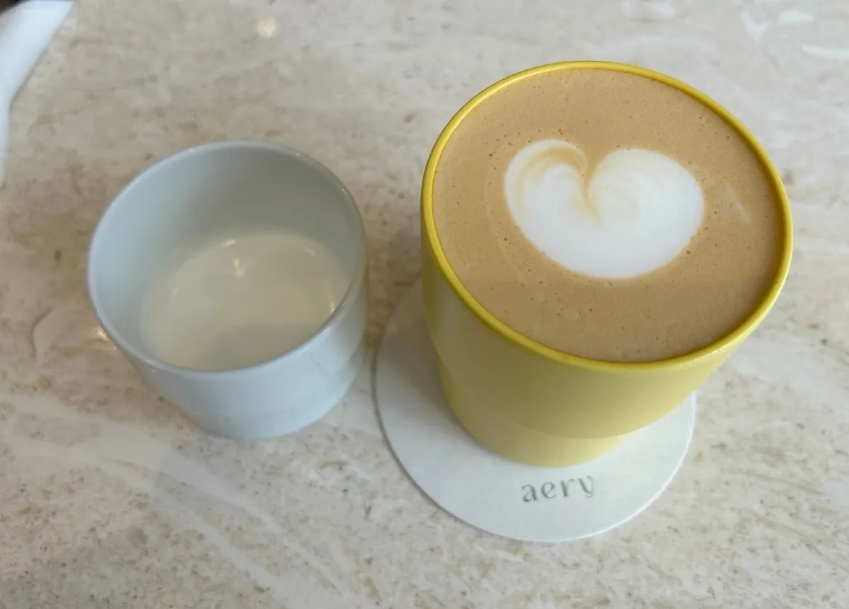 aery coffee — 黄色いカップのハート模様のラテ