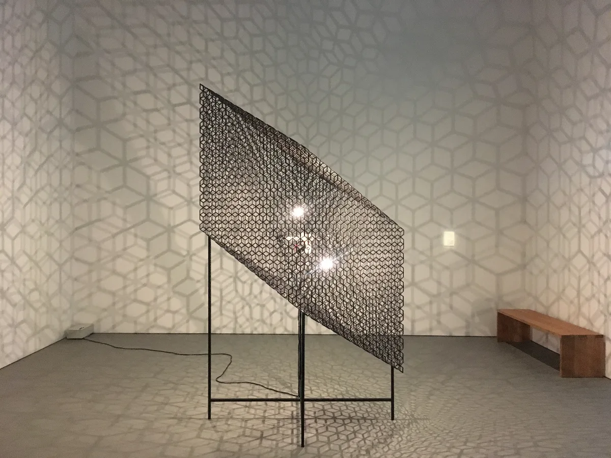 壁一面に幾何学模様の影を映す作品