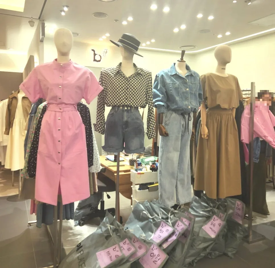 apM PLACE — マネキンに着せた服と出荷用の袋が並ぶ売り場