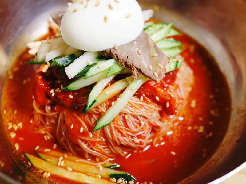 肉と卵をのせた赤いタレの冷麺