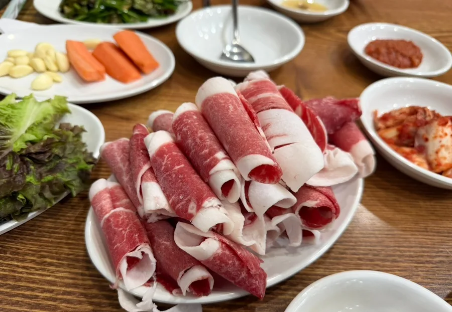 百済精肉店 — 皿に重ねた薄切り牛肉