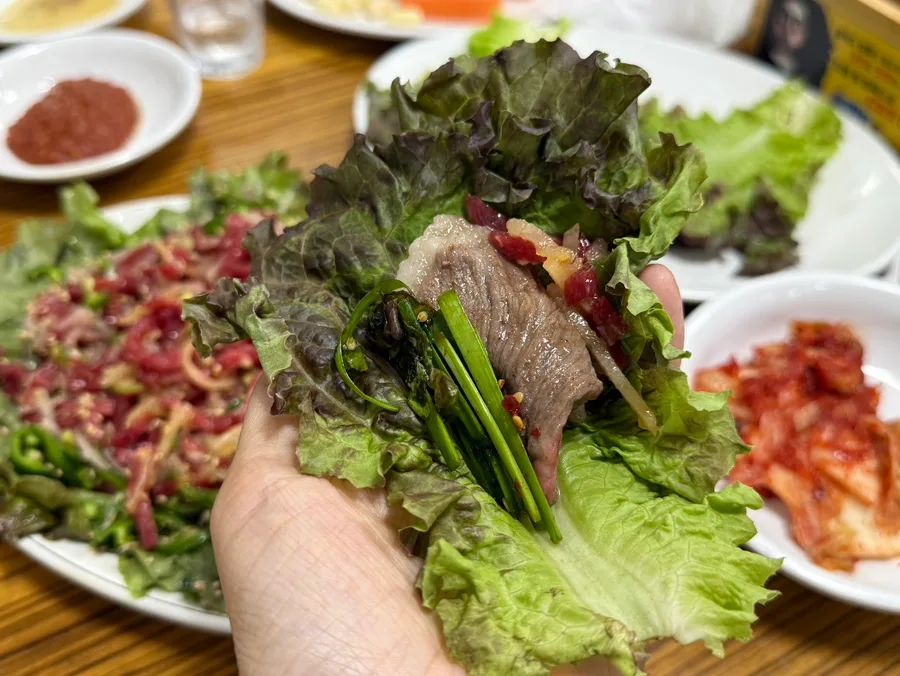 焼いた牛肉とユッケをサンチュで包むところ
