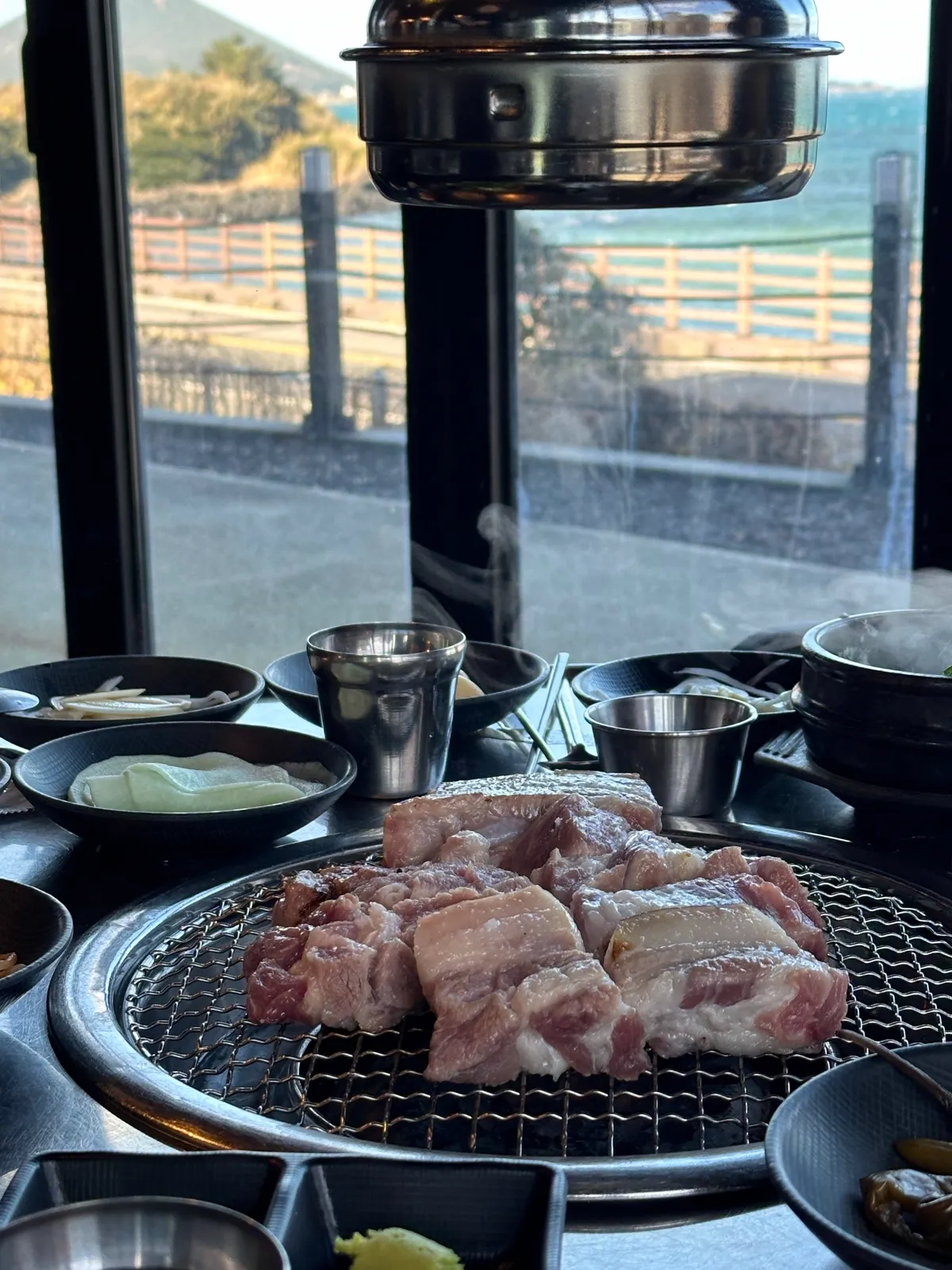 海が見える窓際の席で網にのせた豚肉