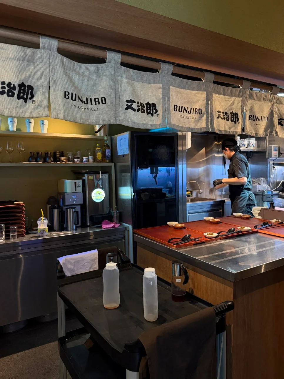 文治郎 サウンズ漢南店 — 文治郎ののれんが掛かるオープンキッチン