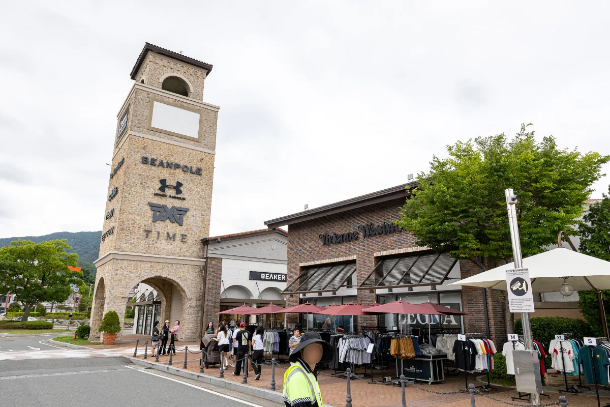 釜山プレミアムアウトレット — ブランドの看板が並ぶ石造りの塔