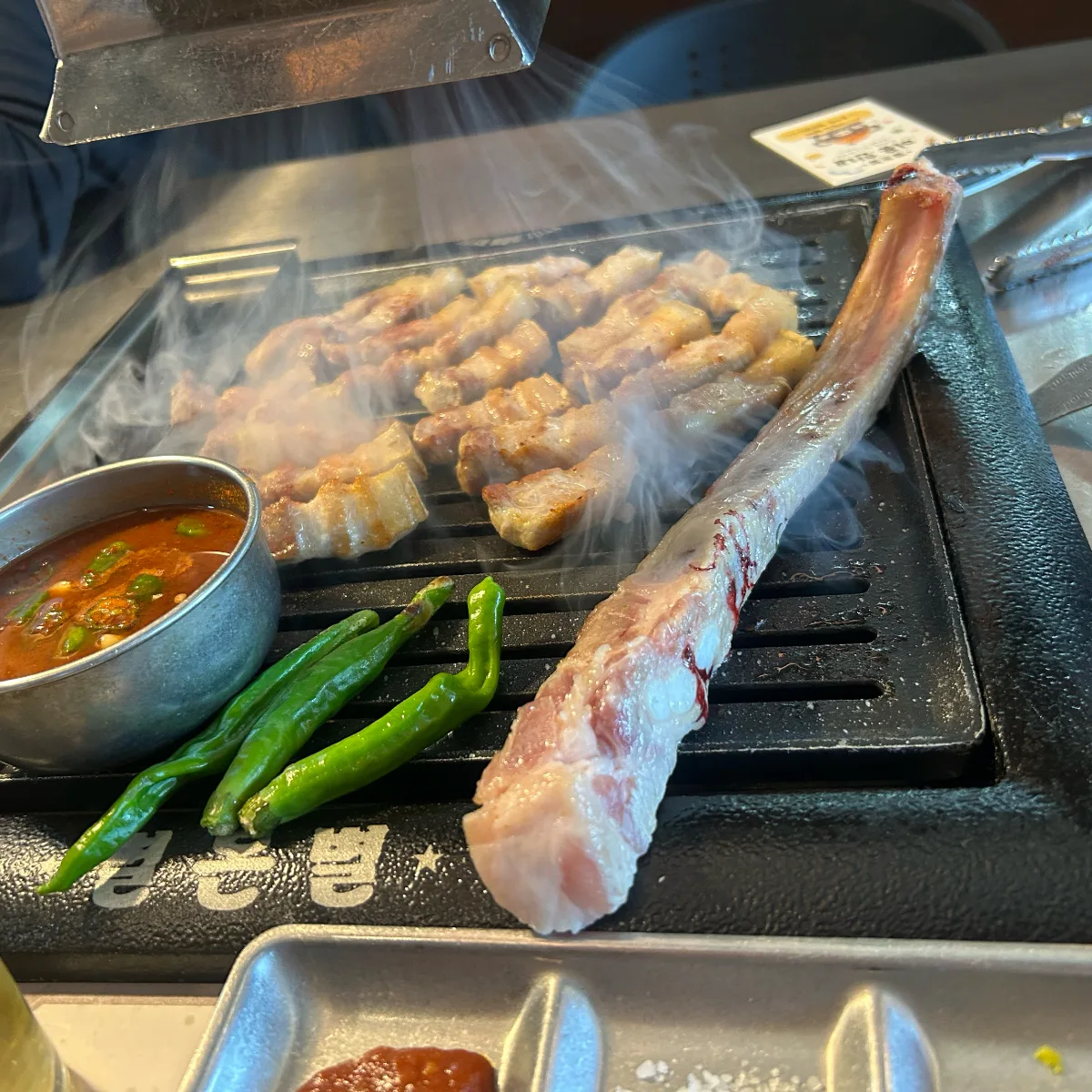 骨付きのバラ肉を鉄板で焼くところ