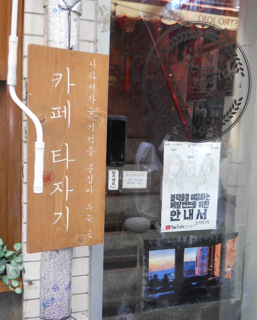 カフェタジャギ — 木の看板が掛かるガラスの入口