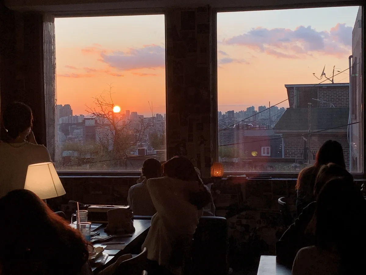 カフェタジャギ — 窓の向こうに沈む夕日と街並み