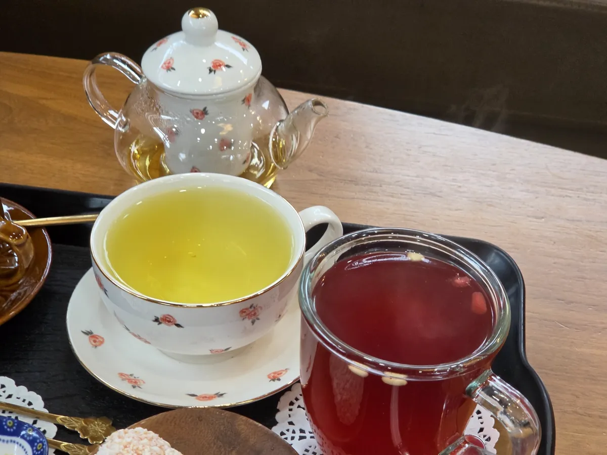 ティーポットの花茶と赤いお茶のグラス
