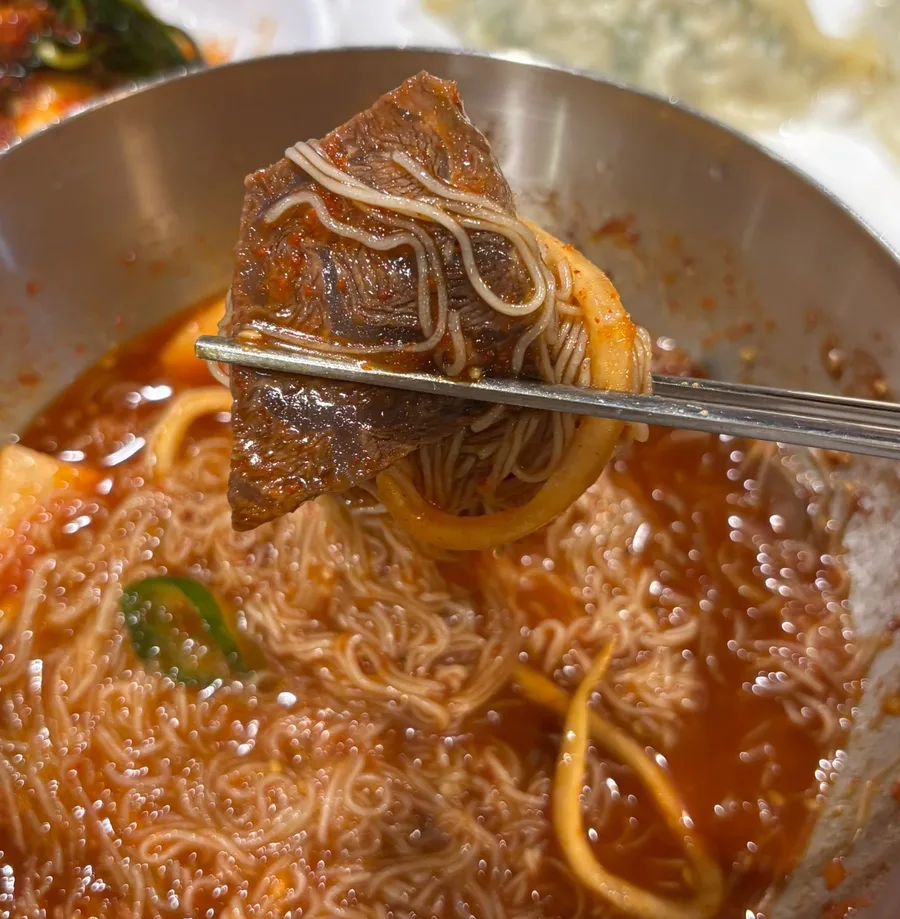 箸で持ち上げた冷麺と牛肉