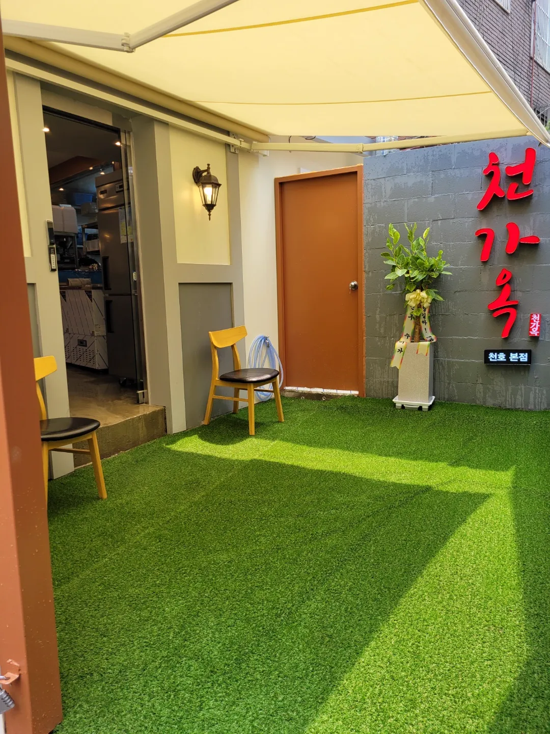チョンガオク — 人工芝の待合スペースと店の入口
