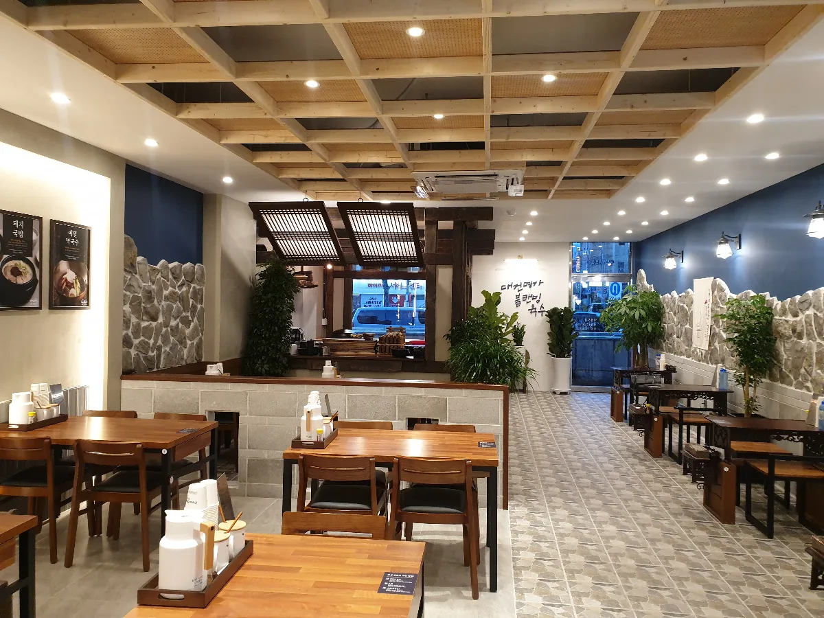 大建名家テジクッパ — 木のテーブルと石壁の店内