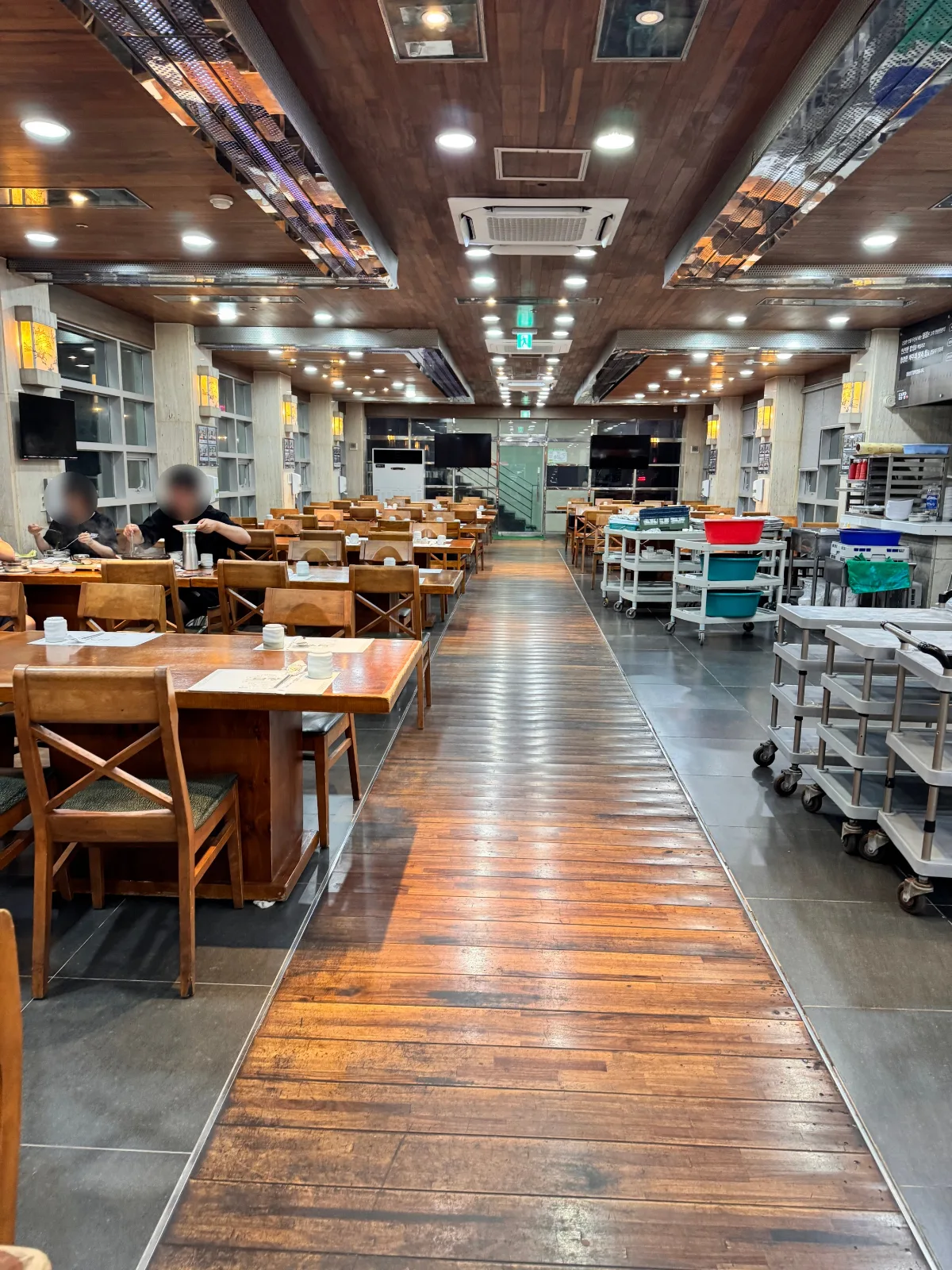 トムジャン 中文店 — 広い通路に沿って並ぶ木のテーブル