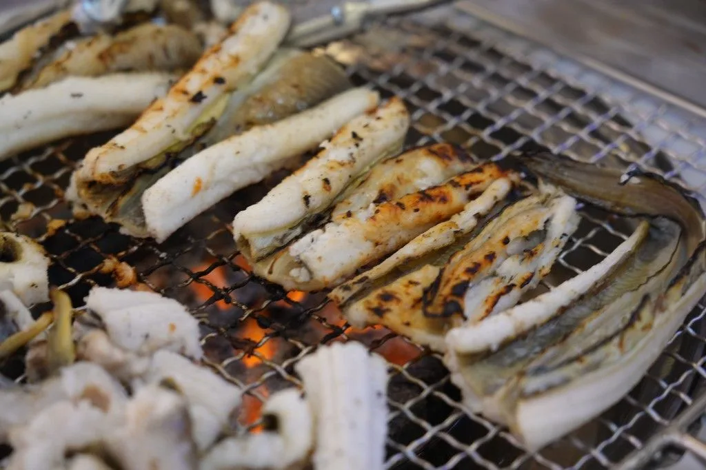 炭火の網で焼けるアナゴ