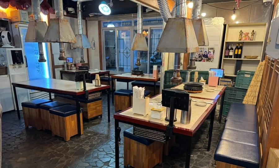 島山トゥッペギ 清潭店 — 排煙フードが並ぶテーブル席