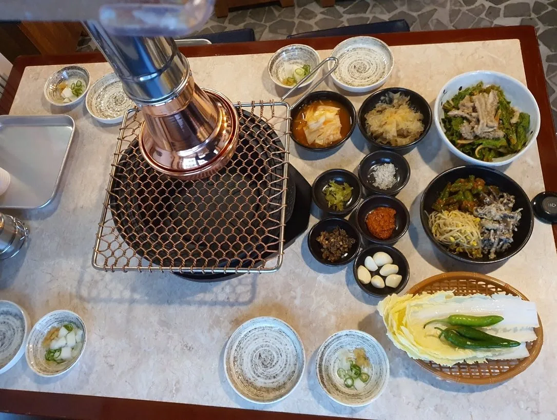 島山トゥッペギ 清潭店 — 焼き網を囲む小鉢と葉野菜