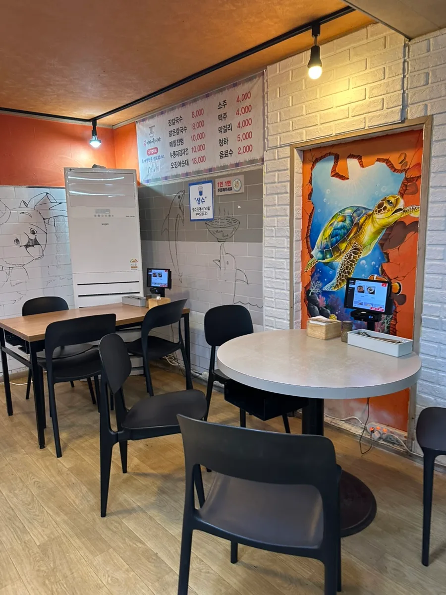クミヤ・オギヤ — 丸テーブルと黒い椅子が並ぶ店内
