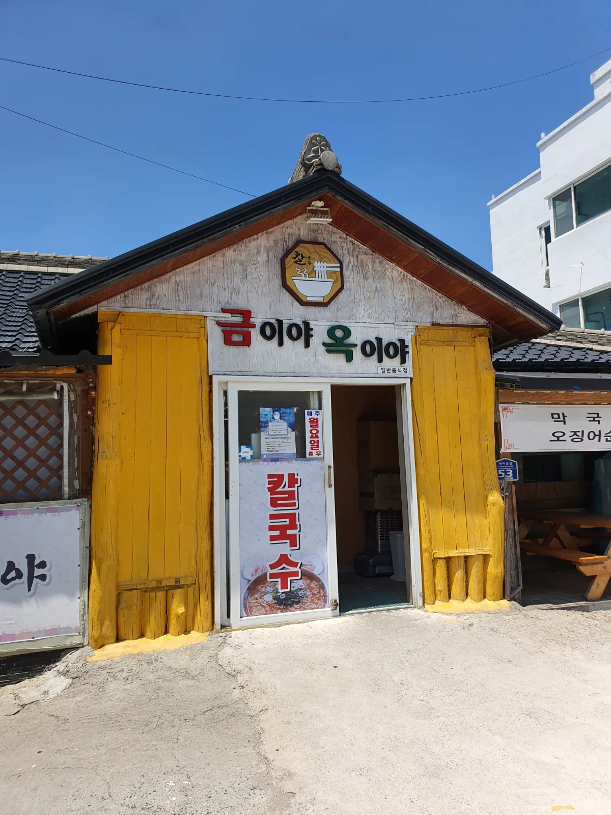 クミヤ・オギヤ — 黄色い壁と店名看板のある入口