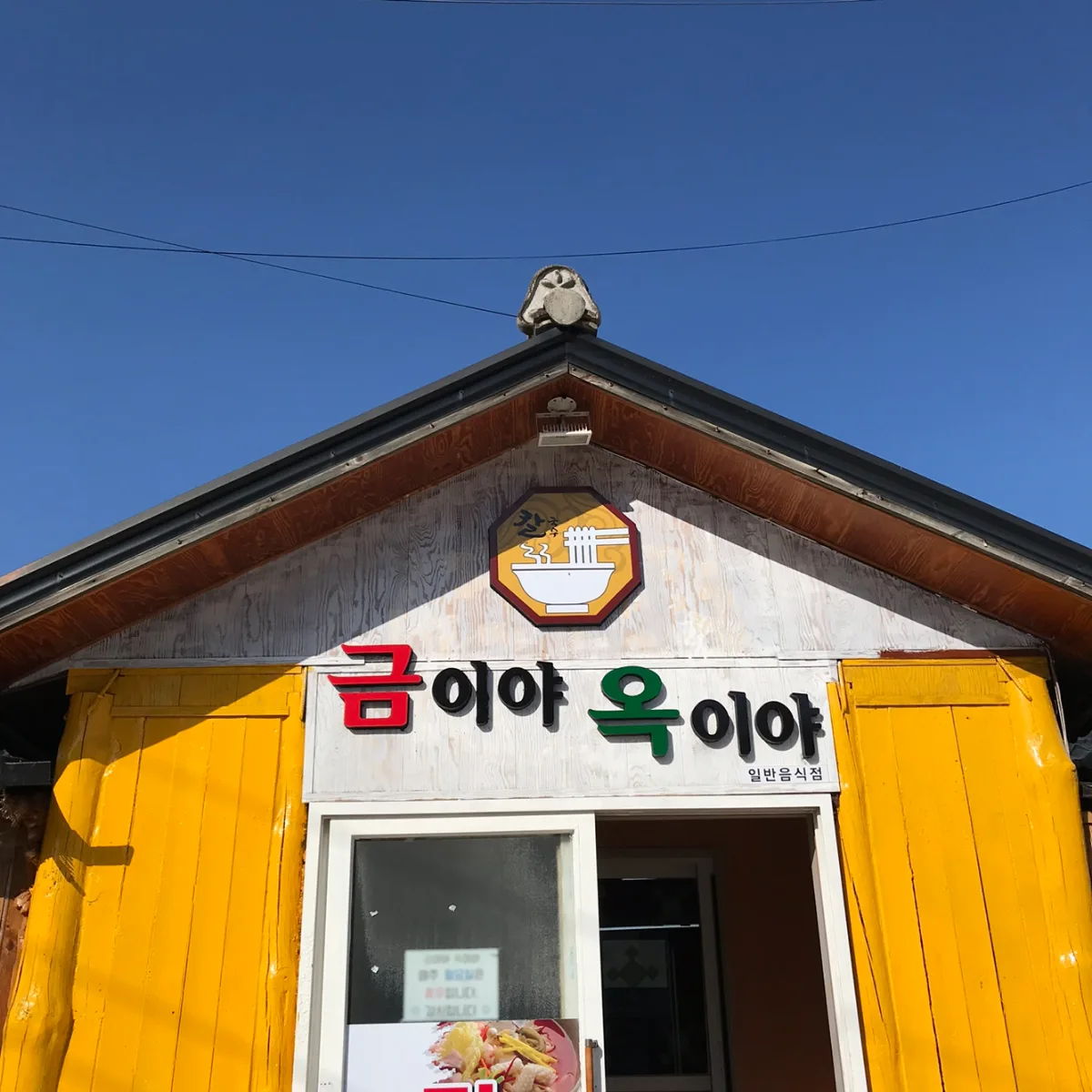 クミヤ・オギヤ — 黄色い扉と店名の看板