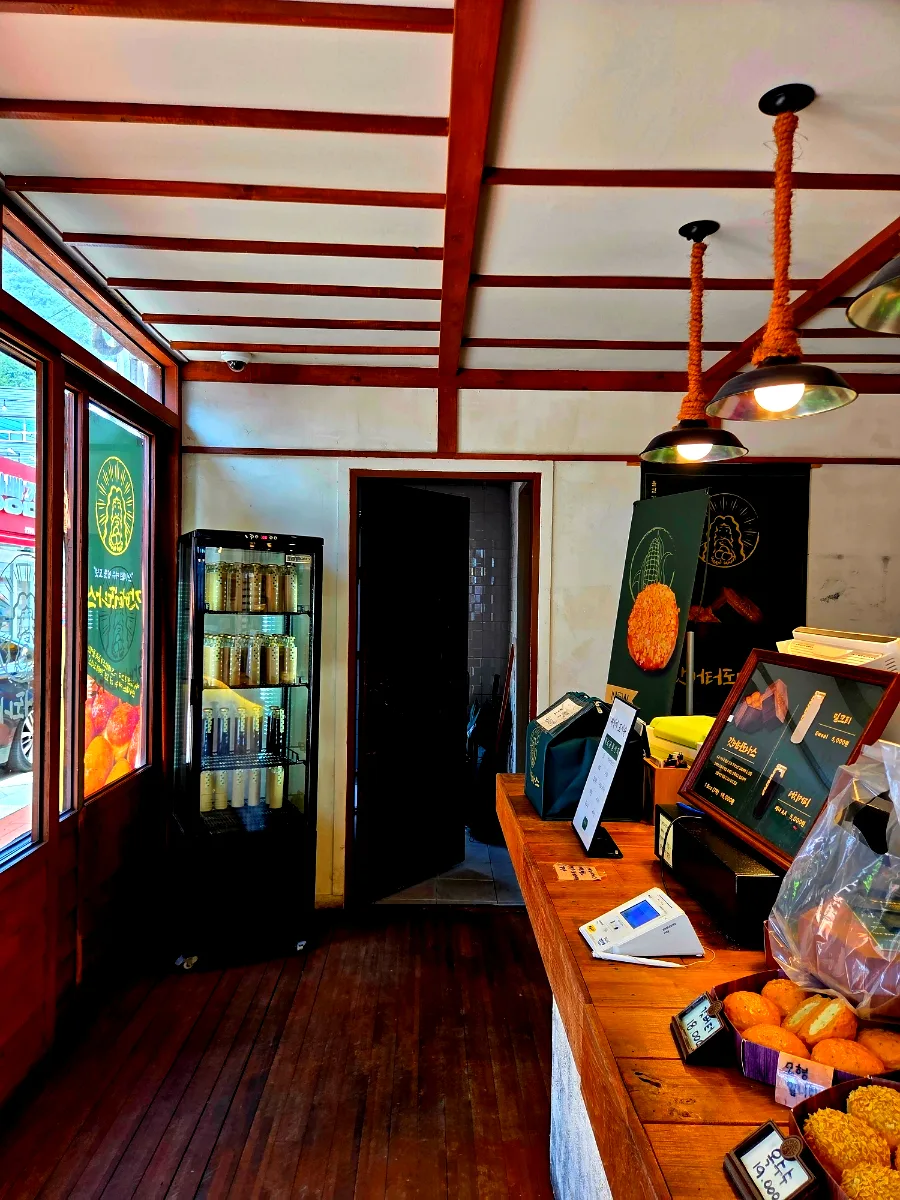 ガットバタードナス 麗水本店 — 木のカウンターと瓶入り飲料の冷蔵庫