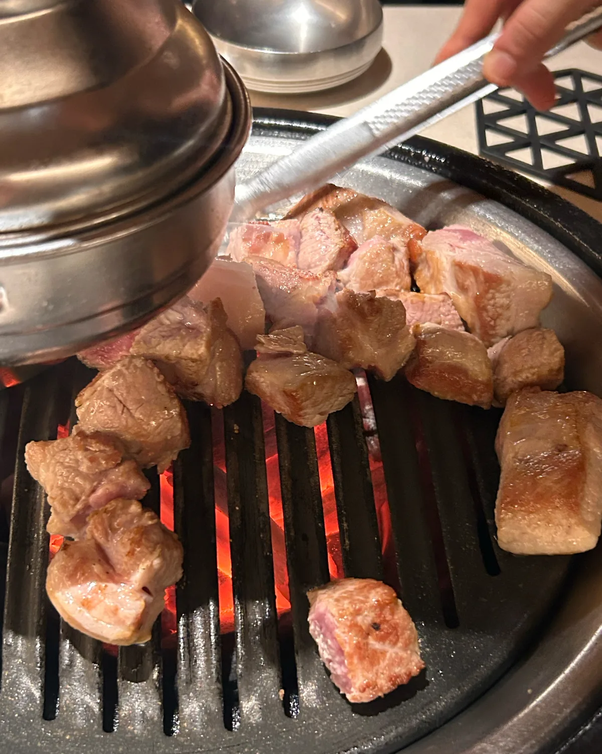 炭火の網で焼く厚切りの豚肉