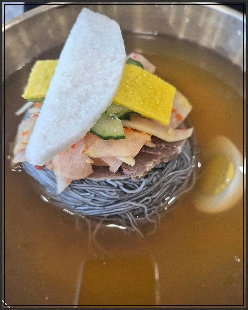 冷たいスープに錦糸卵と大根をのせた水冷麺