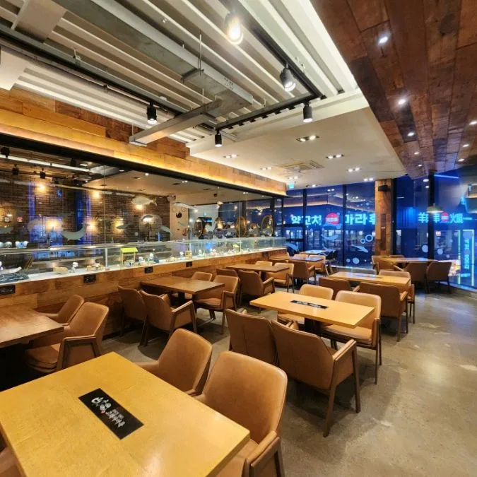 古来思オムッ 海雲台店 — 木のテーブルが並ぶ飲食スペース