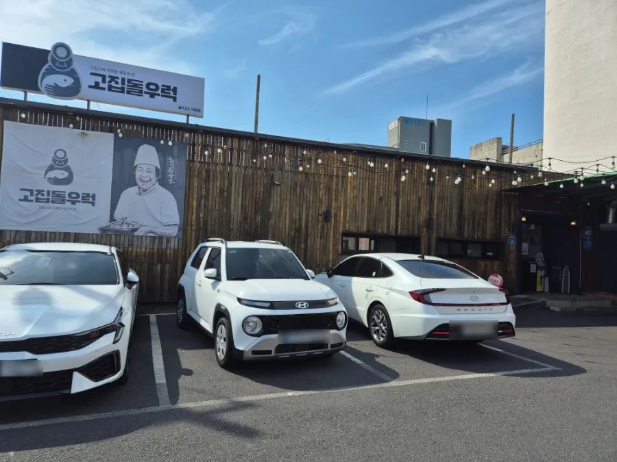 コジプトルロク 済州空港店 — 木の塀と看板が見える店舗と駐車スペース