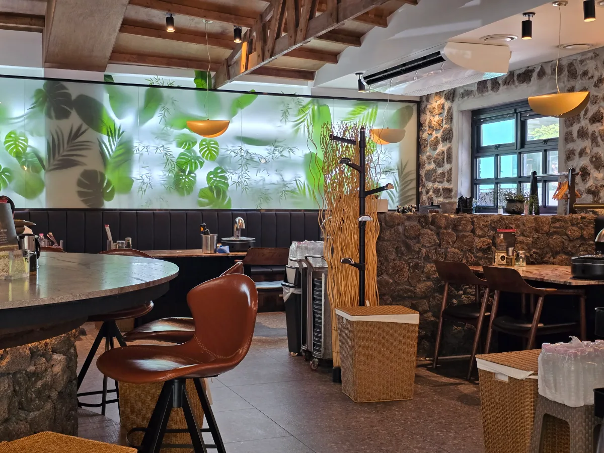 GWANGPYUNG 三成本店 — 植物柄の壁に沿う客席