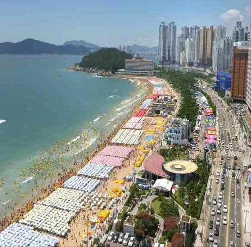 夏の浜を埋めるパラソルと高層ビル