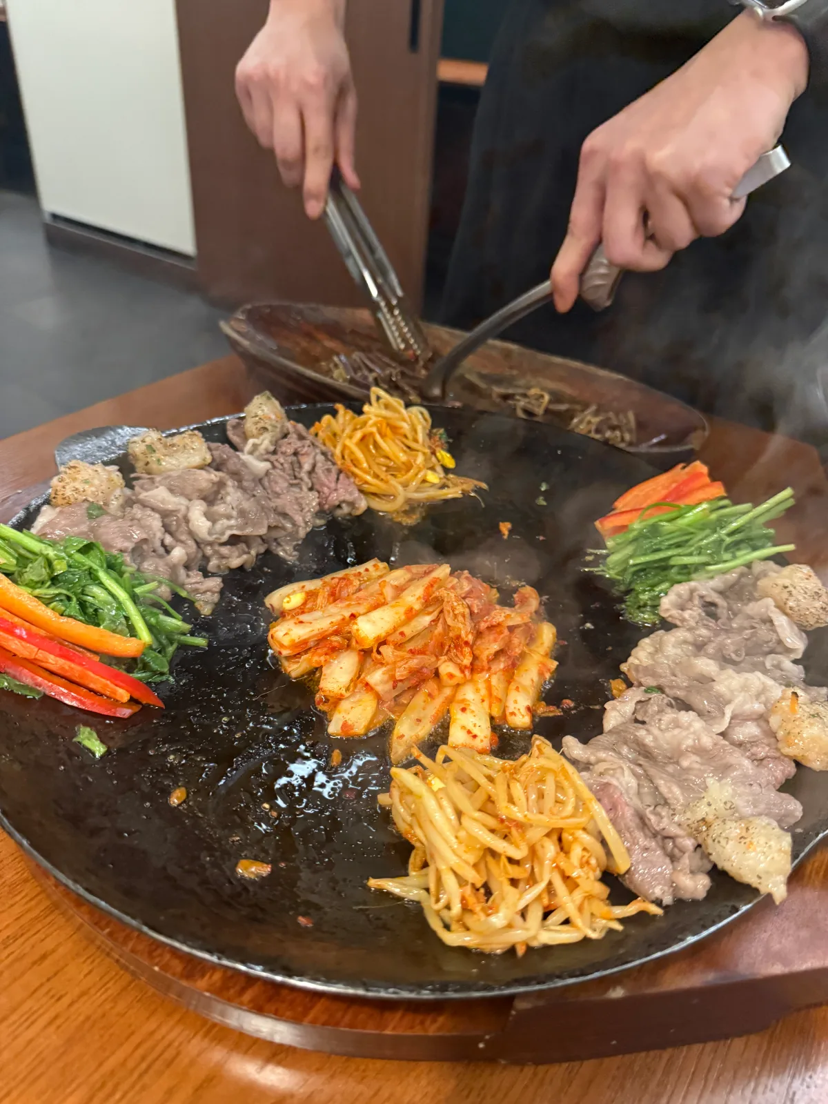 鉄鍋で肉と野菜を焼く場面