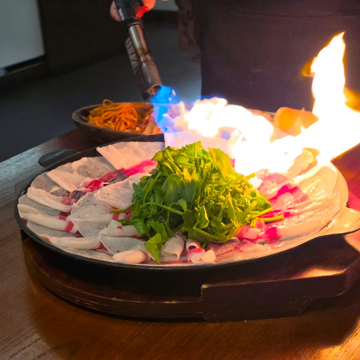 バーナーの炎で牛バラ肉をあぶる場面