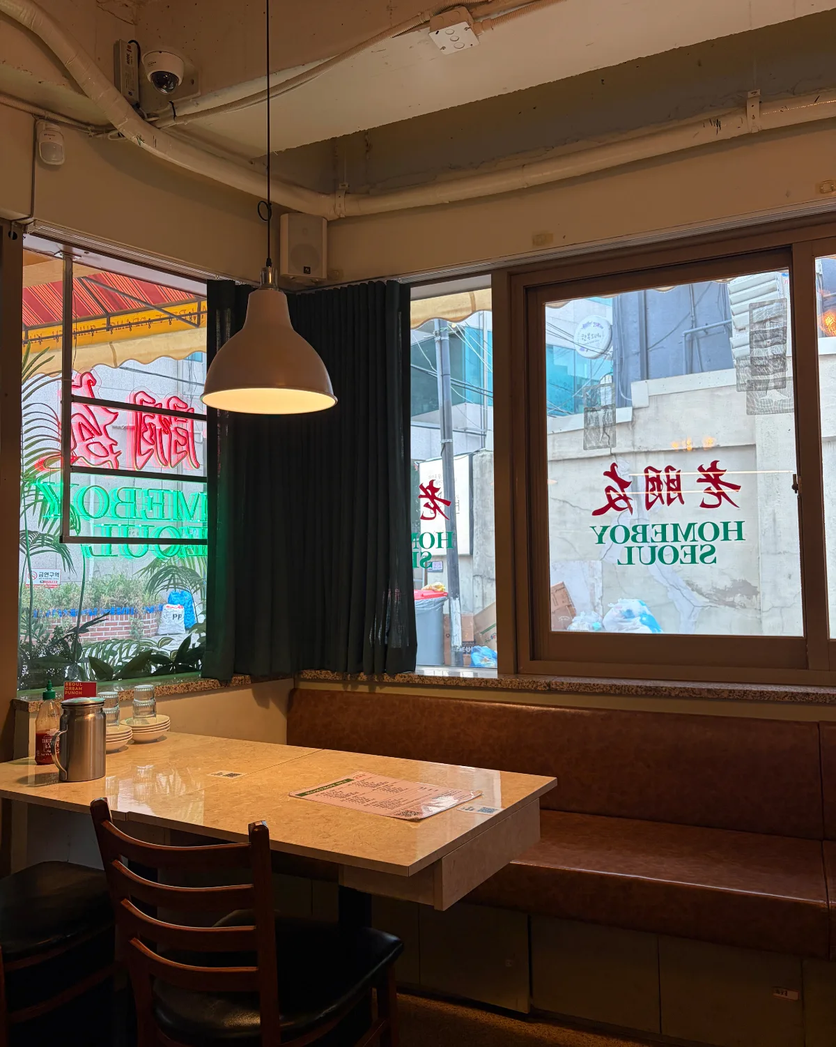 HOMEBOY SEOUL — 窓際のテーブル席と茶色のベンチ