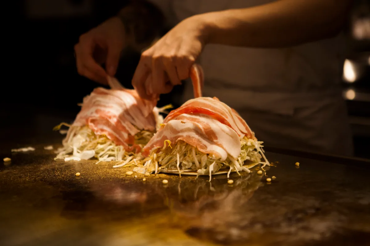 鉄板の上でキャベツに豚肉を重ねていく様子