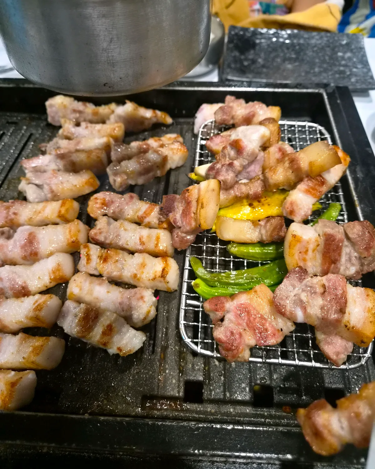 鉄板で焼く豚肉と網に並ぶ野菜