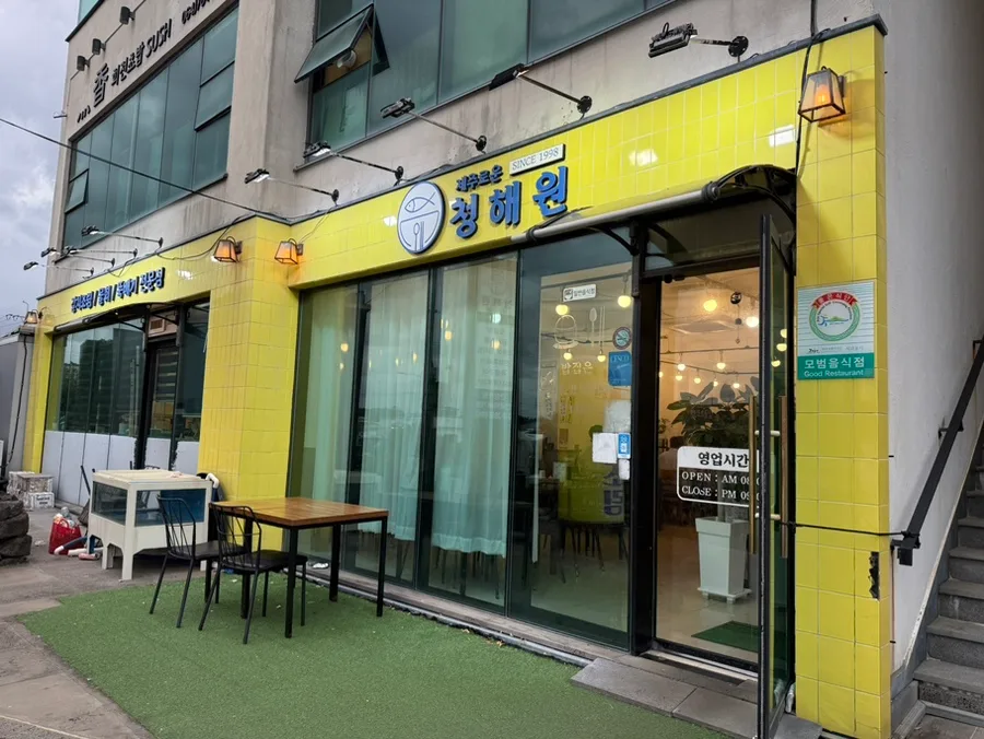チェジュロウン・チョンヘウォン 城山日出峰店 — 黄色いタイルと青い看板の店構え