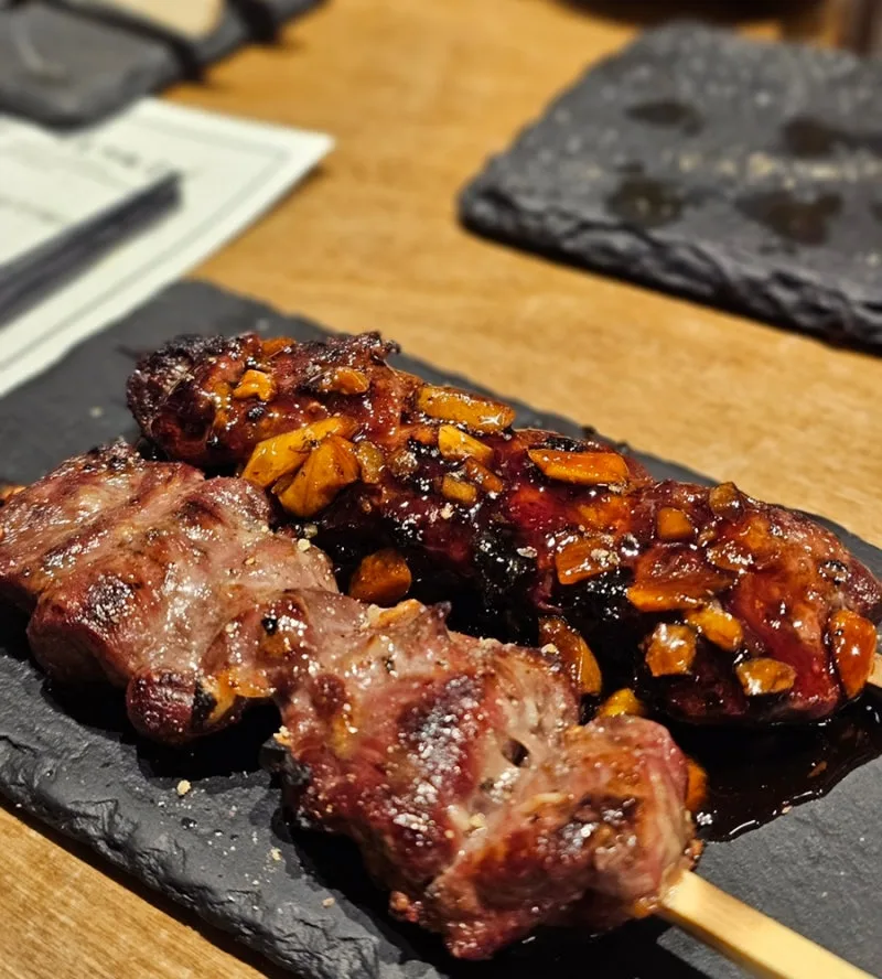 黒い皿に盛った焼き肉の串
