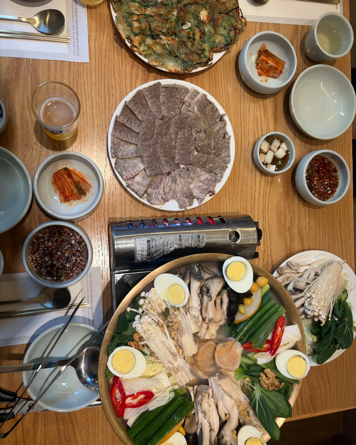 JINJIN MANDU 市庁店 — 鍋とゆで牛肉、チヂミが並ぶ食卓