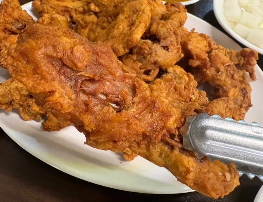 トングで持ち上げた骨付きチキン
