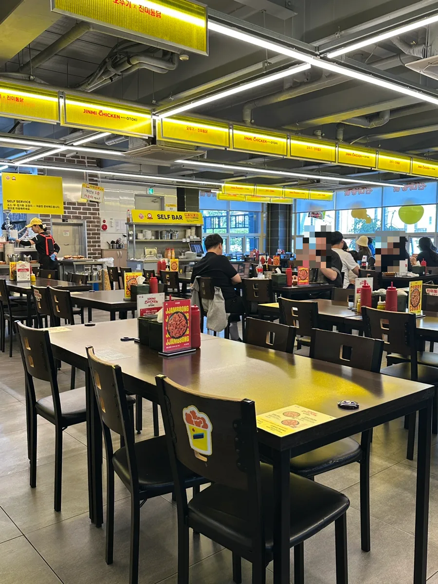 チンミトンタッ — 黄色い看板とテーブルが並ぶ店内