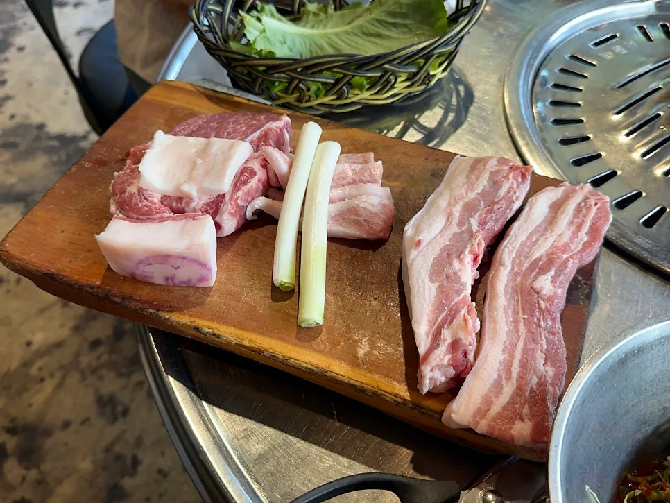 クンドンガ 中文店 — 木の板に並んだ黒豚と白豚の生肉