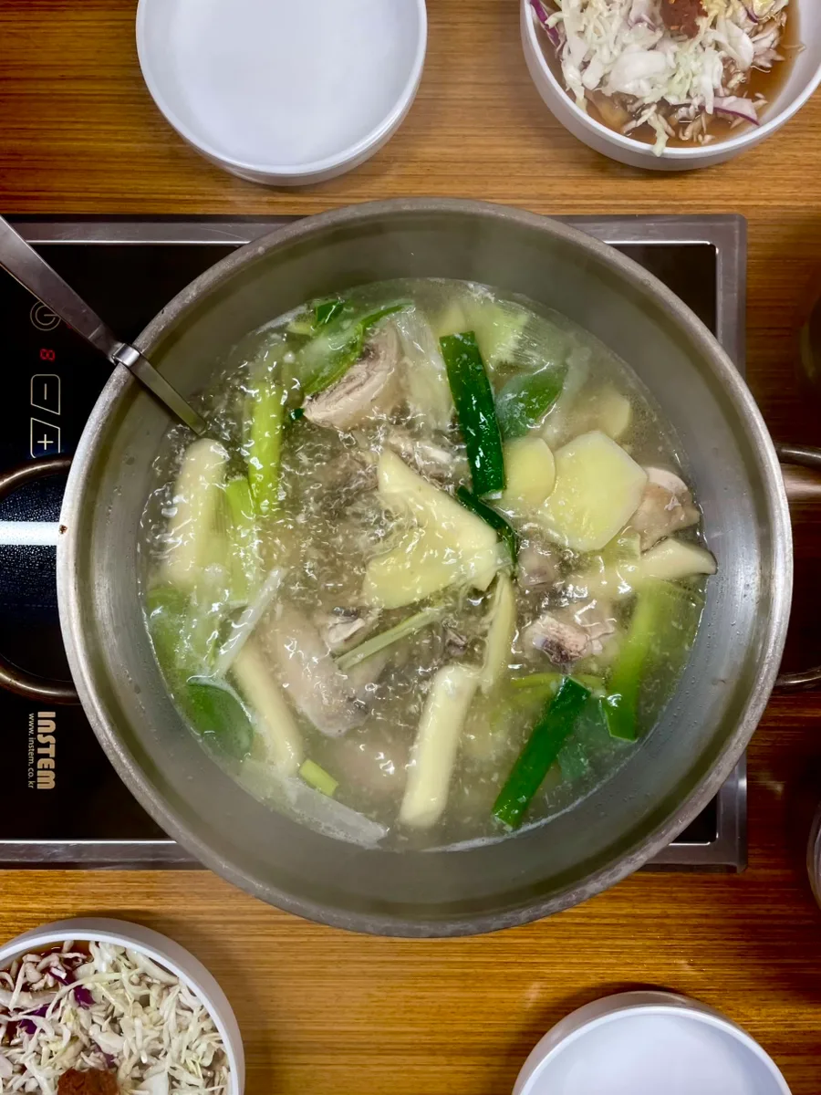 煮立つ鶏鍋とキャベツ入りのタレ