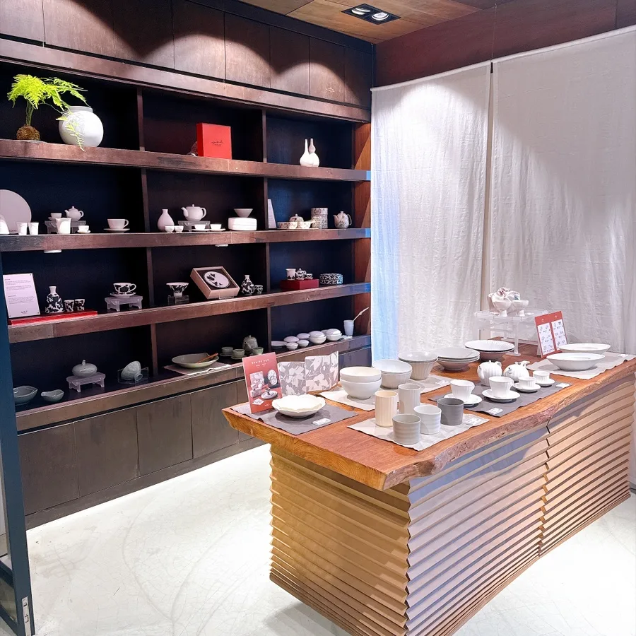 廣州窯 漢南店 — 食器が並ぶ木製台と濃茶の棚