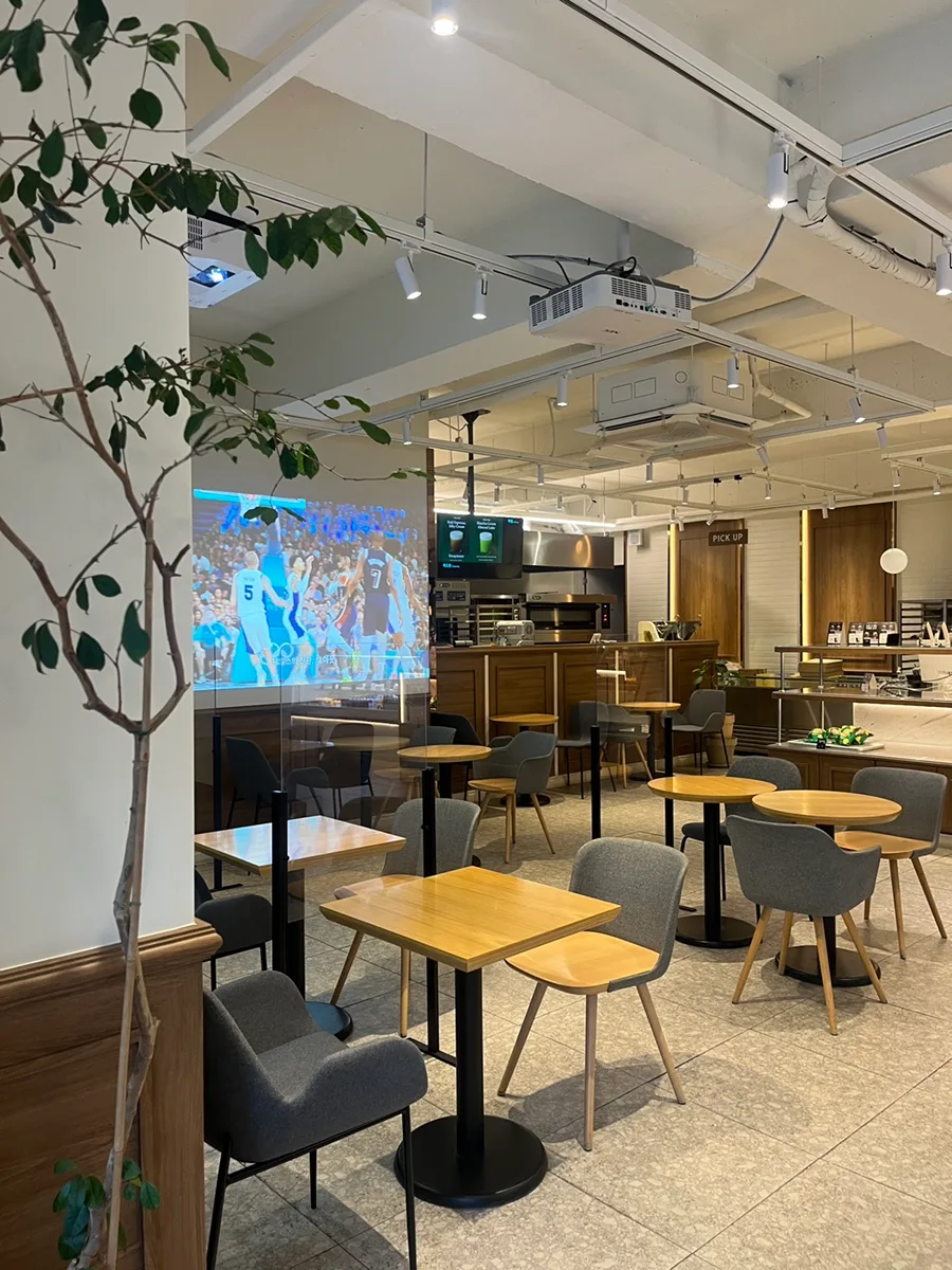 LOCALS. — 木のテーブルとグレーの椅子が並ぶ店内