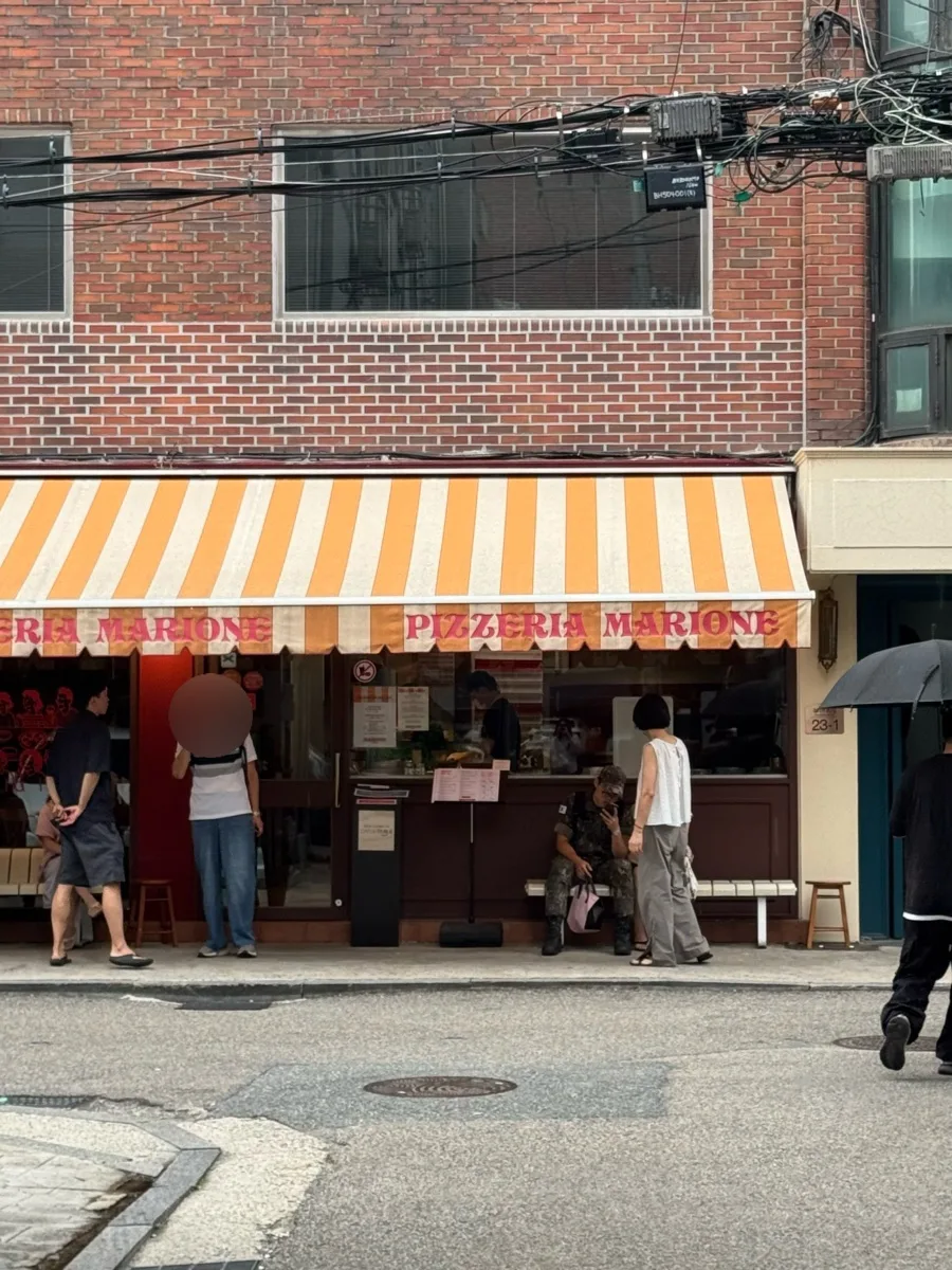 店先で待つ人々と縞模様の日よけ